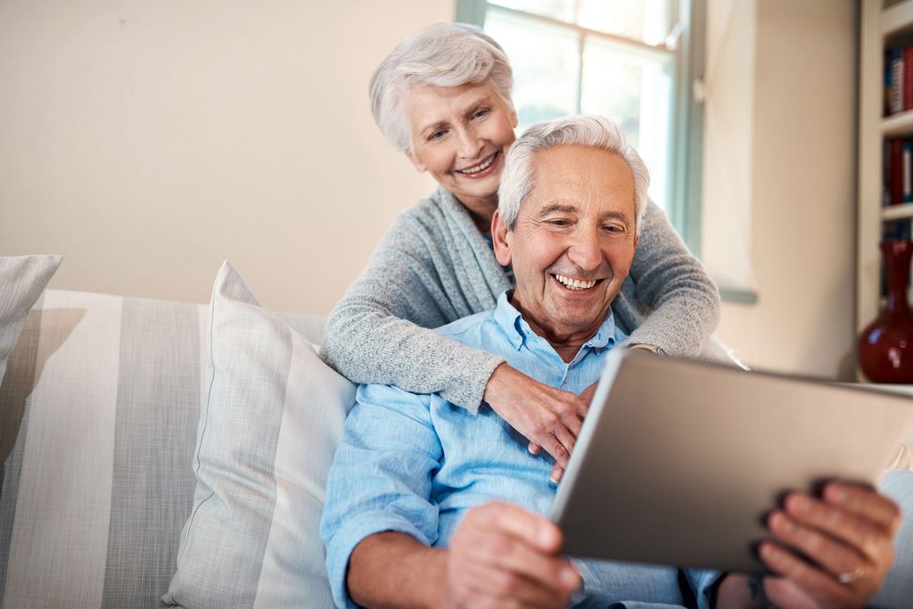 senior couple smiling and looking at tablet